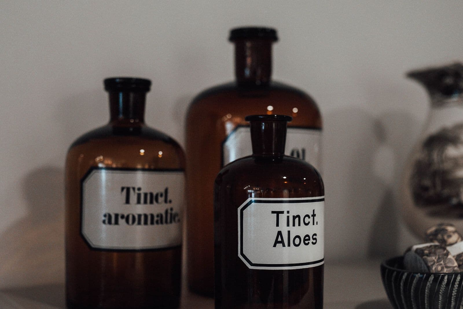 Three labelled apothecary tincture bottles on a shelf in warm, even light.